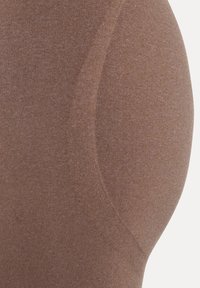 Brune leggings lavet af et tekstureret stof med en buet søm langs siden og en glat finish, der fremhæver det tætsiddende design.