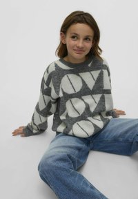 Pull en gris et blanc, avec des motifs géométriques et le texte "AMOUR". Tissu tricoté, col rond et manches longues. Porté avec un jean bleu.