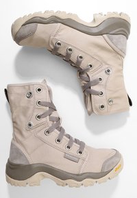 Béžové vysoké boty s plátěným svrškem, šedými akcenty, šněrovacím designem, gumovou podrážkou a strukturovanými gripovými vzory. Logo Columbia na straně.