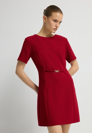 Rood jurk met korte mouwen en een getailleerde silhouet, met een gouden riemgesp detail op de taille. Glad materiaal met een gestructureerde vorm.