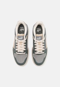 Baskets Puma avec un dessus en cuir gris et vert, accents beige, bout perforé et lacets crème. Comprend une languette rembourrée et un détail de logo.