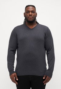 Maglione grigio a V con maniche lunghe, polsini e bordo a costine, realizzato in un morbido tessuto a maglia, caratterizzato da una leggera trama melange.