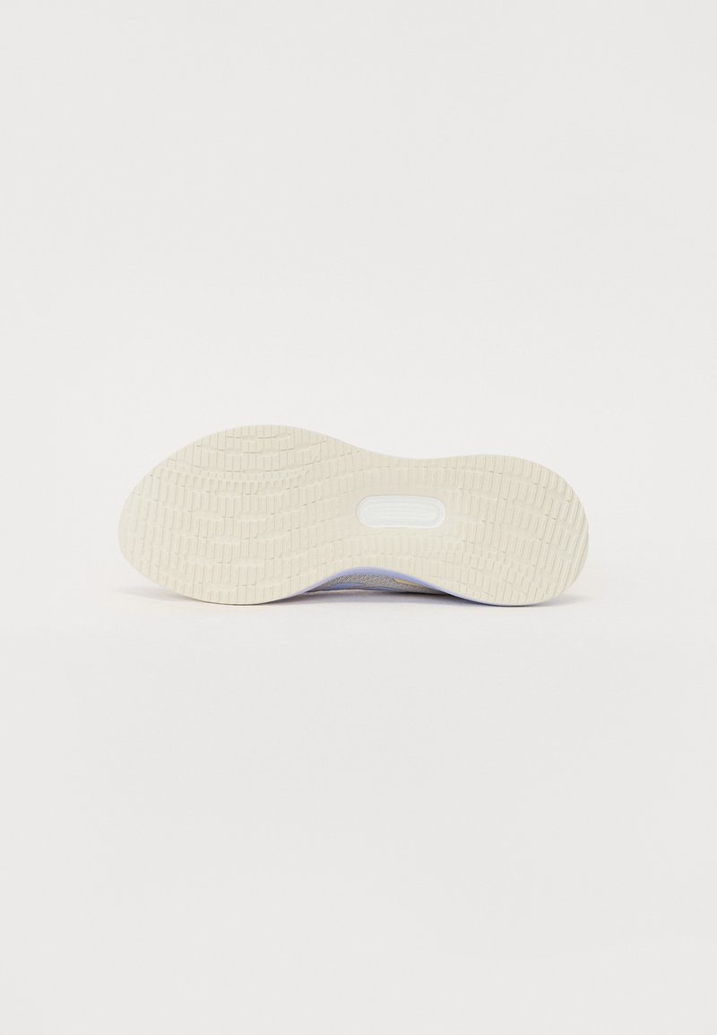 Suela de zapato en color crema claro con un patrón de agarre texturizado, forma ligeramente curvada y un corte central para la característica de amortiguación.