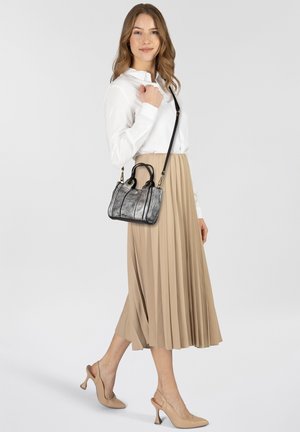 Sac à main en cuir noir et gris avec un design structuré, deux poignées supérieures et une bandoulière réglable, associé à une jupe beige plissée.