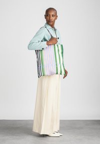 Flerfärgad randig tygväska med gröna, rosa och blå ränder. Tillverkad av tyg, med en mjuk textur och en stabil design.