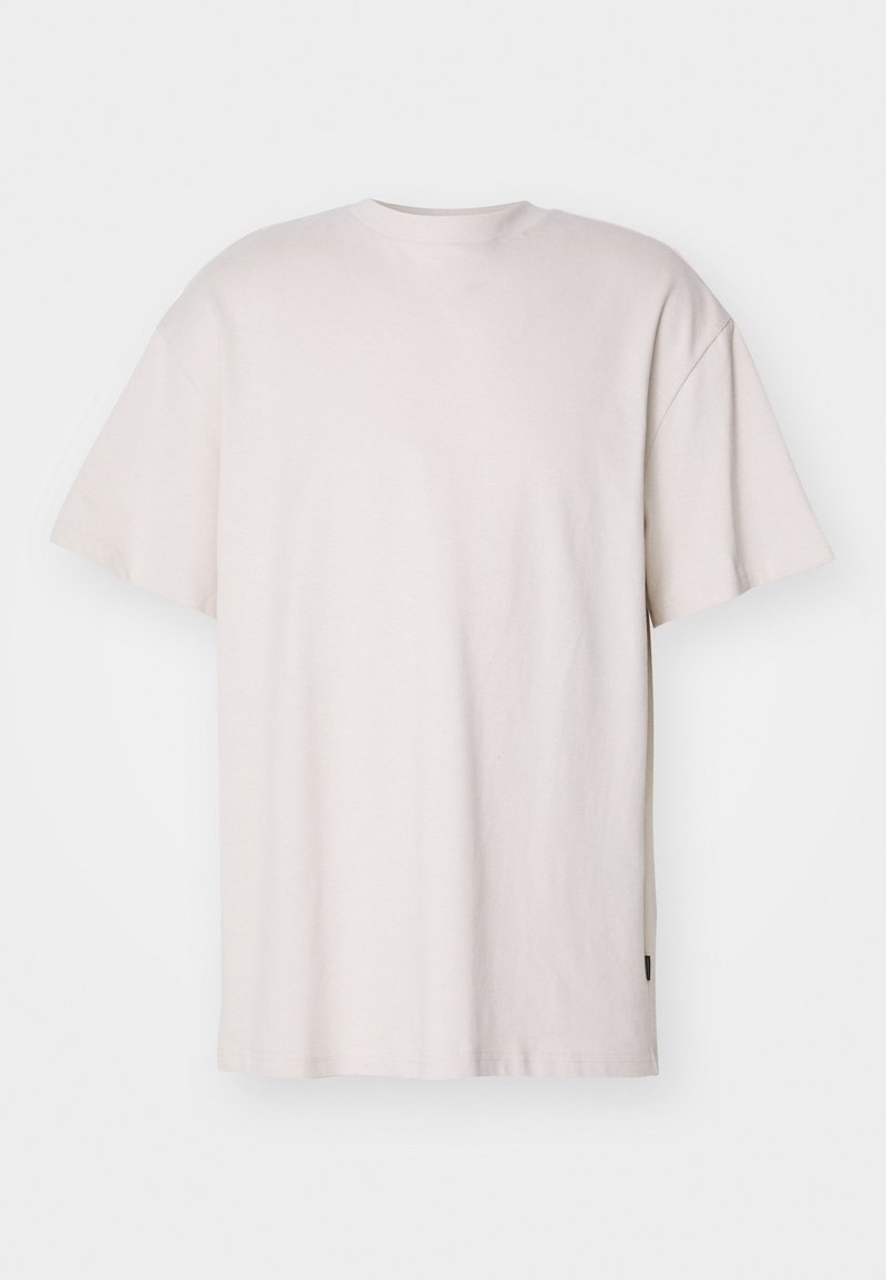 Svetle béžové tričko, krátké rukávy, kulatý výstřih, vyrobené z měkké bavlny. Má volný střih a malou černou etiketu na lemu.