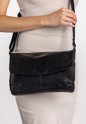 Zwarte leren crossbodytas met flapsluiting, zachte textuur, rechthoekige vorm en verstelbare band. Eenvoudig, functioneel ontwerp.