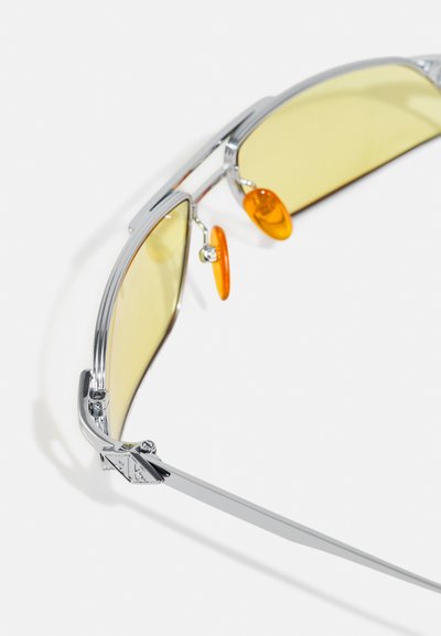 Silver metal sunglasses with yellow lenses, oval shape, adjustable nose pads, and unique orange accents on the frame.