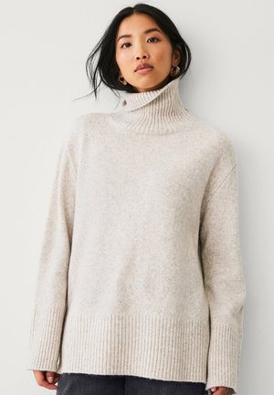 Maglione a collo alto grigio chiaro in un morbido knit testurizzato. Presenta un collo e un orlo a costine con maniche lunghe e morbide.