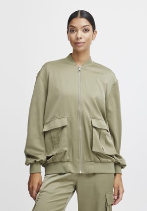 Olivno zelena bomber jakna iz gladkega materiala, z dvema sprednjima žepoma, zadrgo in prilegajočim se pasom.