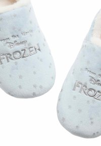 Jasnoniebieskie, puszyste kapcie z srebrnym wzorem w gwiazdki, z haftowanym logo "Kraina Lodu". Miękki, pluszowy materiał zwiększa komfort.