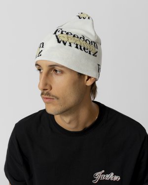 Gorro de punto blanco con el texto "Freedom Winterz" en negro y amarillo. Textura suave con un diseño cónico y ajustado.