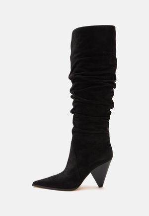 Botte noire en daim décontractée montant jusqu'au genou, avec un bout pointu et un talon haut géométrique en forme de cône.