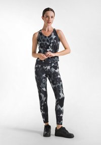 Zwart en grijs gestreept sportoutfit bestaande uit een mouwloos topje en aansluitende broek, gemaakt van een gladde, rekbare stof.