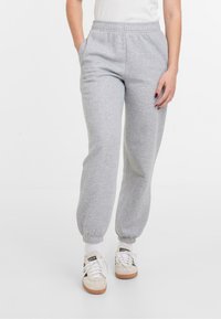 Pantalon de jogging gris en tissu doux, doté d'une taille élastique, de poches latérales et de poignets élastiques aux chevilles.