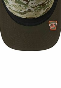 Cap mit einem Frontteil im digitalen Camouflage-Muster in Grüntönen und Brauntönen, schwarzem Schirm und einem orangefarbenen Logo an der Seite. Weicher Stoff, strukturierte Gestaltung.