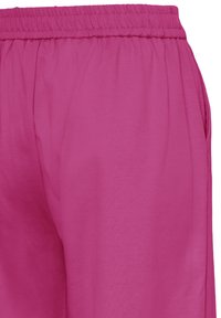 Rózsaszín pamut jogger nadrág elasztikus derékpánttal, oldalzsebekkel és sima textúrával, deréktől a combig bemutatva.