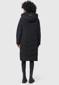 Manteau en duvet noir avec un design en chevrons, dotée d'une capuche et de détails à boutons pression, descendant jusqu'à mi-mollet. Fabriqué en matériau léger.