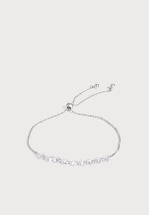 Braccialetto delicato regolabile in argento con piccoli cristalli trasparenti a forma di cubo infilati sulla catena su uno sfondo chiaro semplice.
