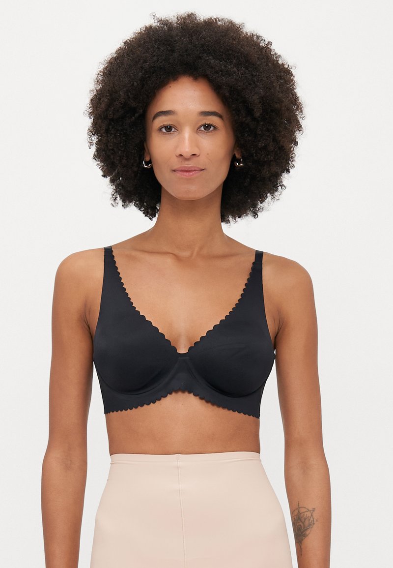 Μαύρο σουτιέν με κυματιστό κόψιμο, λεία ύφανση και στήριξη με μπανέλα. Διαθέτει ρυθμιζόμενες τιράντες και σχέδιο σε V.