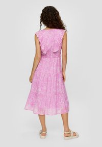Roze midi-jurk met bloemenpatronen, ruffled cap sleeves, elastische taille en een gelaagde rok. Gecombineerd met lichtgekleurde platform sandalen.
