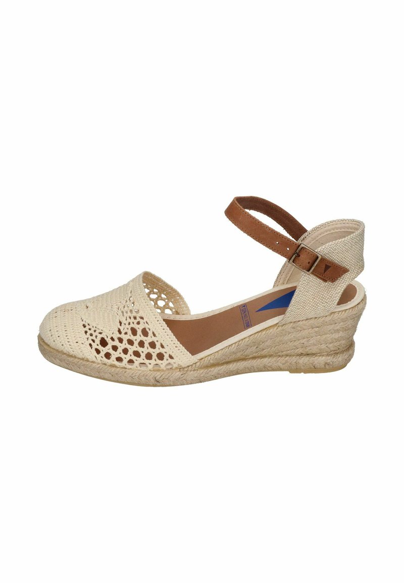 Sandalia de cuña con parte superior de fibra natural trenzada, diseño de punta abierta, color beige claro, correa en el tobillo marrón y suela de yute texturizada.