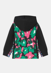 Mikina s kapucí, která má černý přední díl a živý květinový vzor v zelené, růžové a bílé barvě na zadní a bočních stranách, s barevným akcentem.