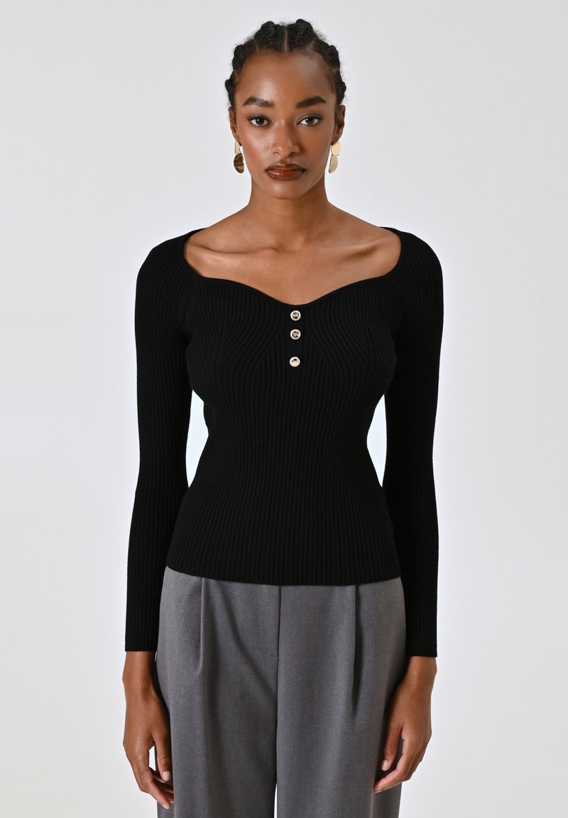 Top lungo maniche nere a costine con scollatura a cuore e tre bottoni dorati sul davanti. Il tessuto appare texturizzato e aderente.