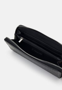 Black textured leather wallet with silver zipper, featuring multiple compartments and a small zip pocket inside, labeled "even&odd."