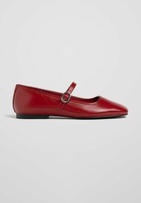 Chaussure plate Mary Jane en cuir rouge avec bout pointu et bride à boucle argentée, vue de profil sur fond blanc.