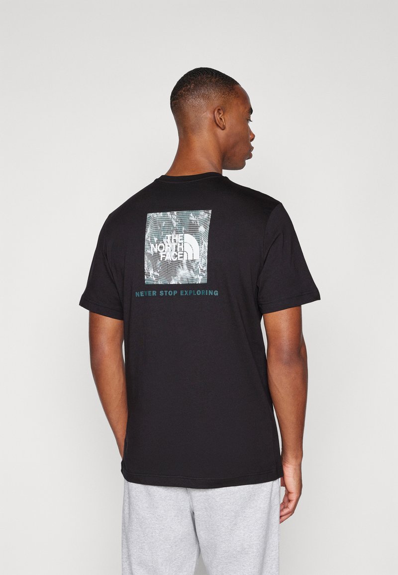 Camiseta de algodón negra con un gráfico cuadrado que presenta un diseño inspirado en la naturaleza y un logo, con el texto "NUNCA DEJES DE EXPLORAR" debajo.