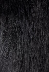 Närbild av raka, glänsande svarta hårstrån med naturlig textur och subtila ljusreflektioner.