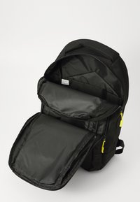 Black backpack with multiple open compartments, yellow zipper pulls, and a padded interior suitable for a laptop or tablets.