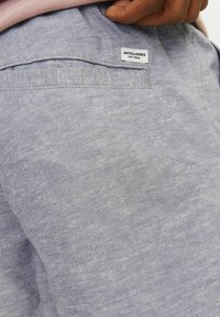 Svijetloplave platnene kratke hlače s teksturiranim završetkom, s stražnjim džepom i bijelom etiketom s natpisom "JACK & JONES EST. 1990".