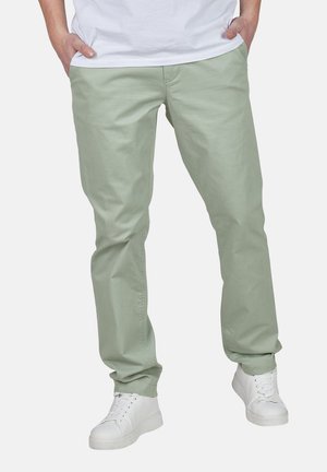 Lichtgroene katoenbroek met een rechte pijp, voorzien van twee voorzakken en een gladde textuur, gecombineerd met witte sneakers.