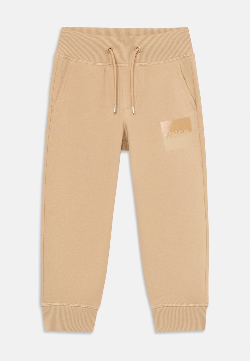 Beige avsmalnande sweatpants med ribbad midja och muddar, dragsko, sidofickor och glänsande "HUGO"-logotyp på vänster lår.