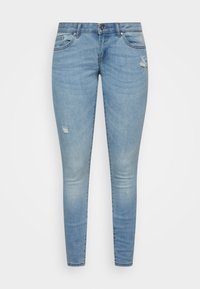 Vaqueros ajustados de denim azul con un acabado desgastado, que presentan un pequeño desgarro en el muslo y un diseño clásico de cinco bolsillos.