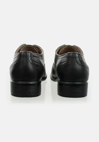Zapatos de cuero negro con una textura suave, punta redondeada, diseño curvado y perforaciones decorativas. Tacón resistente y acabado elegante.