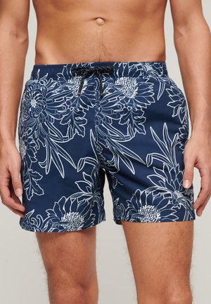 Maillots de bain bleu marine avec un motif floral blanc, ceinture élastique et cordon de serrage ajustable. Fabriqués en tissu léger et à séchage rapide.