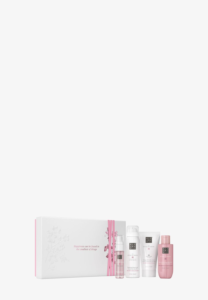 Sett inkluderer fire hudpleieprodukter i rosa og hvit emballasje, presentert i en hvit boks med blomsterdesign og et rosa bånd.