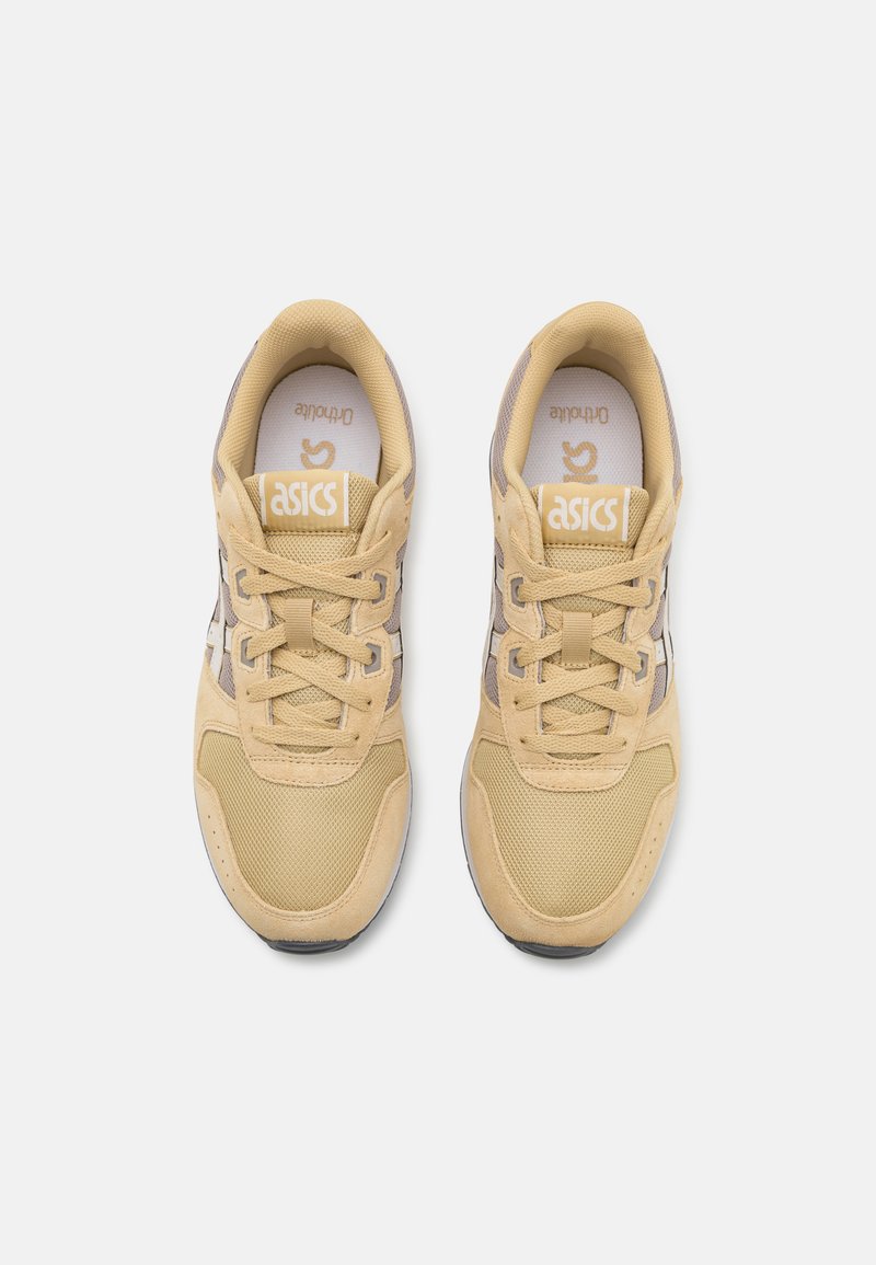 Zapatillas de deporte color beige claro con materiales de malla y ante, con acentos tonales, puntera redonda y suela plana. Logo de ASICS en la lengüeta y los laterales.