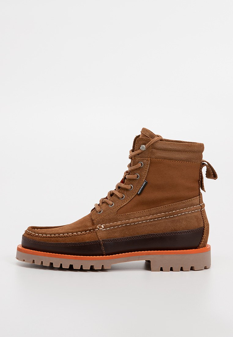 Braune Wildleder- und Leinenschuhe mit gepolstertem Kragen, Schnürdesign, kontrastierenden dunkelbraunen Lederakzenten und einer robusten beigen Außensohle mit orangefarbener Umrandung.