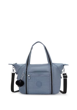 Blue nylon tote bag with dual top handles and a detachable shoulder strap. Features a front zipper pocket and a furry pom-pom accessory.