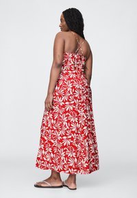 Rød maxikjole med hvidt blomsterprint, spaghetti-stropper og rynket detalje på ryggen. Inkluderer sandaler med gennemsigtige stropper.