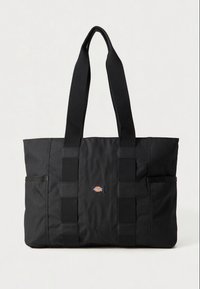 Black tote bag made of durable fabric, featuring two long handles, side pockets, and a small logo patch on the front.