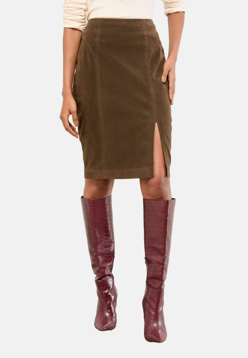 Fustă creion din cord pentru o culoare maro, cu o fâșie laterală, combinată cu cizme burgundy cu textură de crocodil până la genunchi, creând o siluetă ajustată.