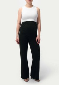 Svart byxdress med vida ben, elastisk midja; kombinerad med en vit ribbad ärmlös topp. Snygg, minimalistisk design och mjuk textur.