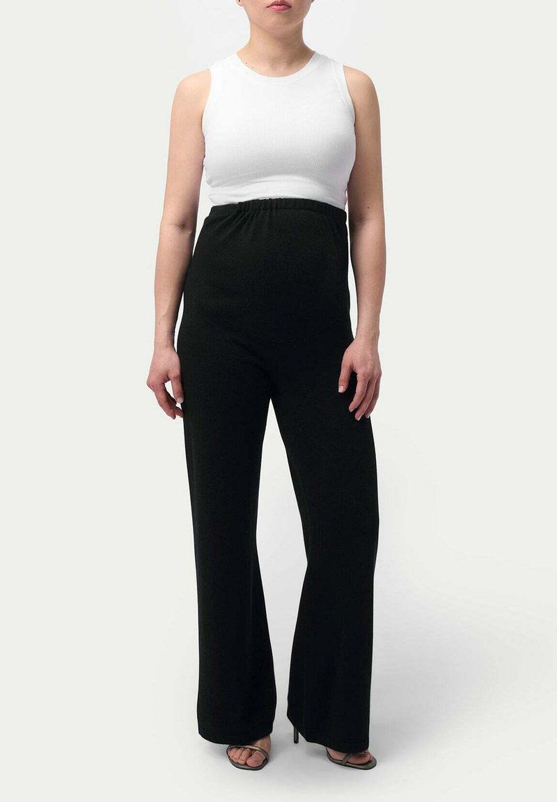 Svart byxdress med vida ben, elastisk midja; kombinerad med en vit ribbad ärmlös topp. Snygg, minimalistisk design och mjuk textur.