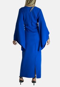 Abito lungo blu con maniche a campana, corpetto aderente e uno spacco laterale. Tessuto liscio di colore uniforme, con minime accentuazioni hardware visibili.