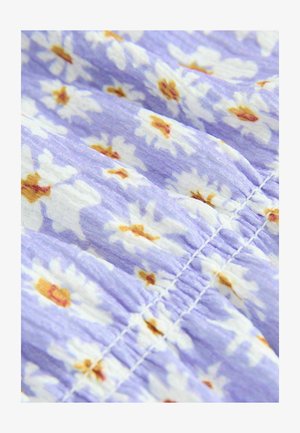 Kwiatowy materiał sukienki w jasnofioletowym kolorze z białymi stokrotkami i żółtymi środkami. Teksturowany z fałdami i detalami zgromadzonego ściegu.